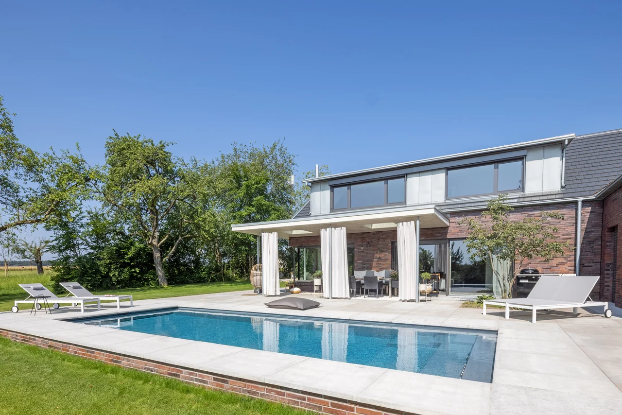 A covered swimming pool terrace with loungers for year round use